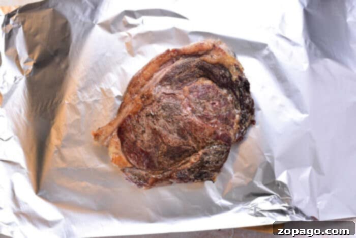 New York Strip Steak 5 A perfectly cooked strip steak, tented with crumpled aluminum foil, resting on a cutting board, a critical step to ensure maximum juiciness after being cooked in the oven.