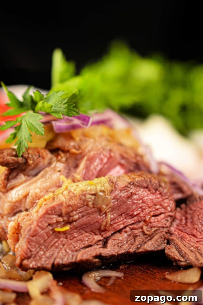 Chuck Roll Steak
A Cut Above: The Chuck Roll Steak Experience 5 Close-up of juicy, medium-rare chuck roll steak garnished with parsley and sliced red onions, with fresh greens in the background.