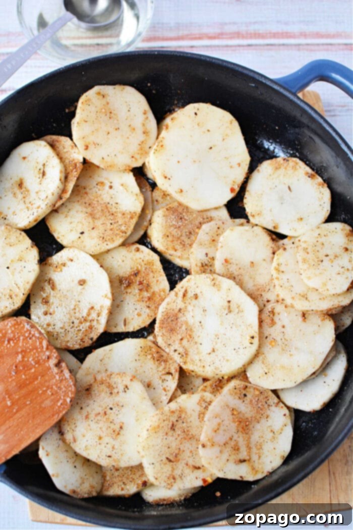 Home Fries 7 A close-up shot of perfectly golden pan fried potatoes with tender onions in a cast iron skillet