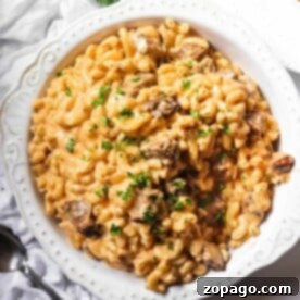 A white bowl filled with creamy macaroni and cheese topped with chopped herbs, a perfect way to use leftover tri-tip.