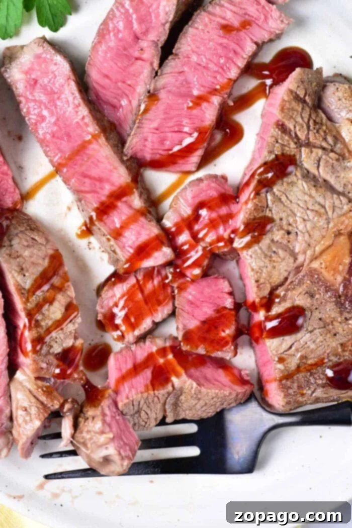 Velvet Oven Steak 2 Melt-in-Your-Mouth Steak in the Oven: A beautifully cooked steak, sliced to reveal a perfect medium-rare pink interior, garnished and ready to serve.