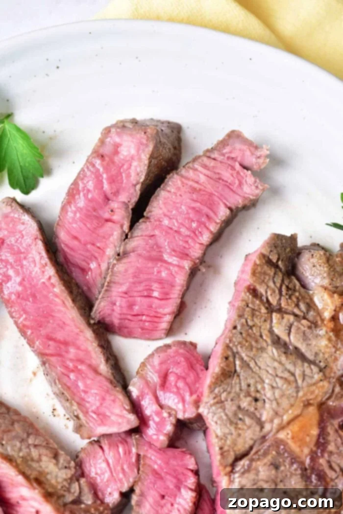 Velvet Oven Steak 8 How to Cook Melt in Your Mouth Steak in the Oven: A close-up view of a steak resting on a cutting board, ready to be sliced, emphasizing its juicy appearance.