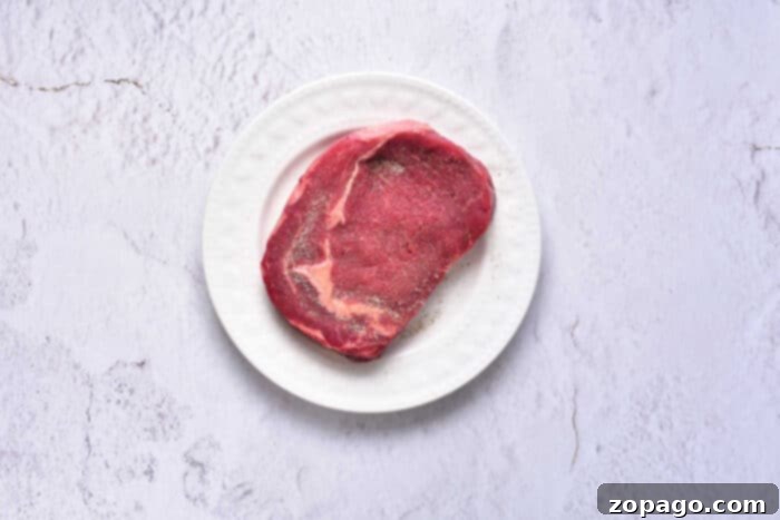 Velvet Oven Steak 9 How to cook mouthwatering steak: A platter of sliced, perfectly cooked steak, adorned with fresh herbs and ready for a gourmet meal.