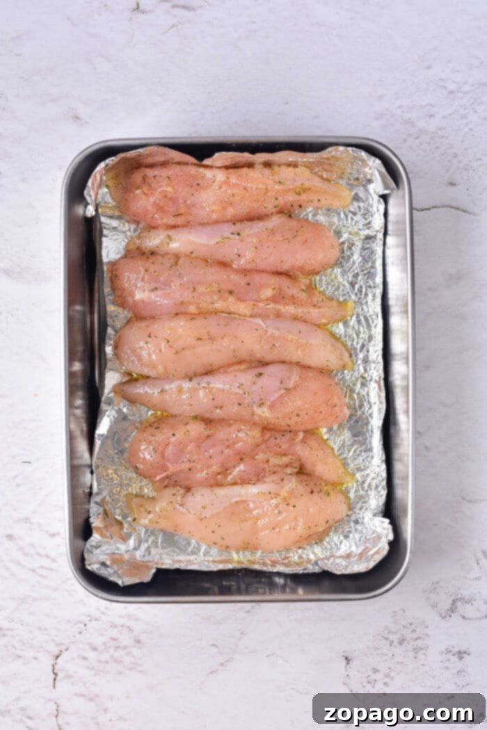 Naked Oven Chicken Tenders 5 A plate of oven-baked chicken tenders, showing the moist interior and crispy edges, ready to be served.