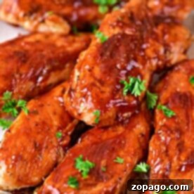 Naked Oven Chicken Tenders 8 Succulent oven-baked chicken tenders glisten with a savory glaze, elegantly garnished with fresh parsley on a plate.