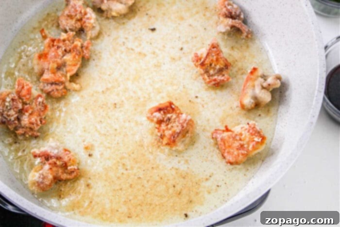 Sticky Honey Garlic Chicken Bites 3 Close-up of crispy chicken bites glistening with sauce in a skillet