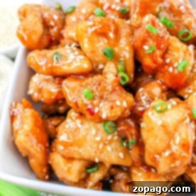 A bowl of glazed sesame chicken bites, garnished with fresh green onions, offers a delightful twist on the classic chicken bites recipe.