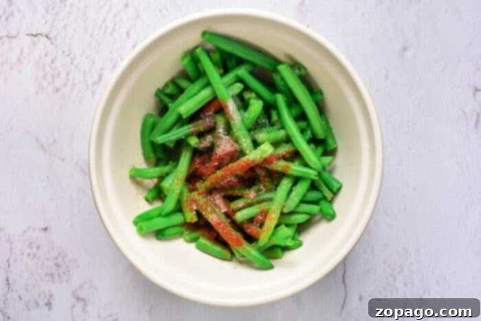 Irresistible Green Beans 4 Close-up shot of green beans mixed with crispy bacon bits, oven-baked to perfection.