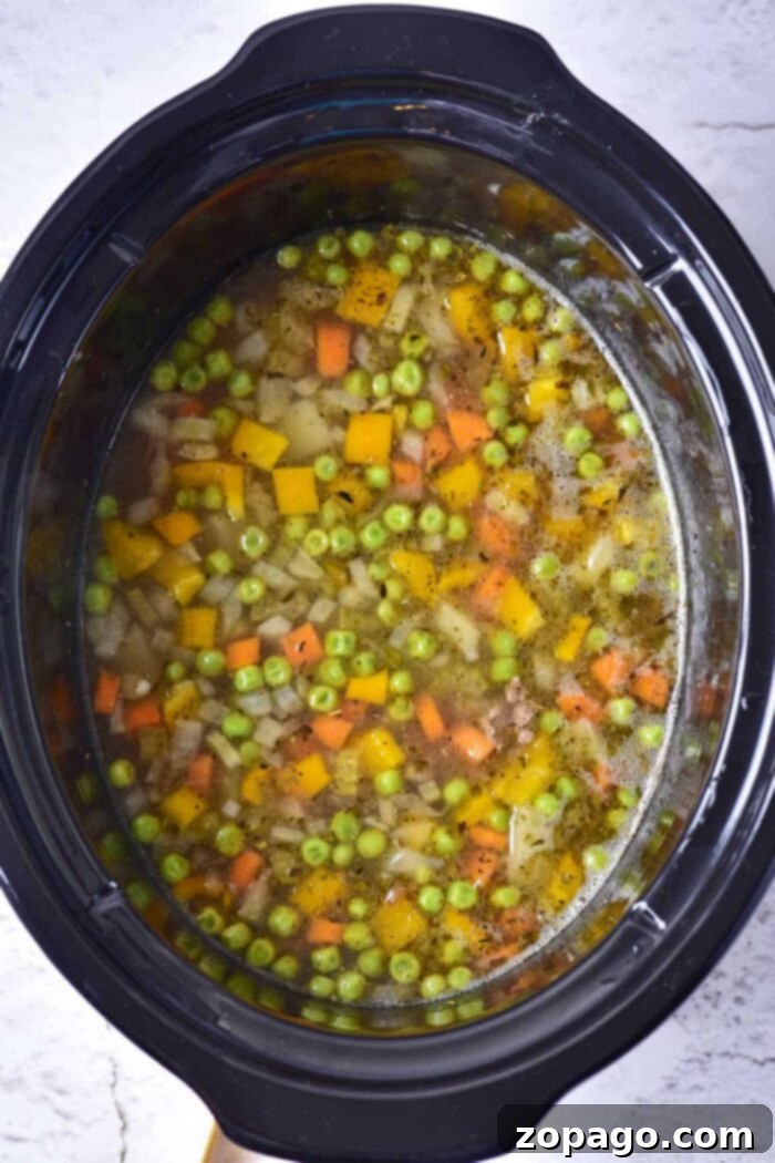 Slow Cooker Creamy Ground Beef and Potato Soup 5 Delicious ground beef soup simmering in a Crockpot, filled with vegetables and rich broth.