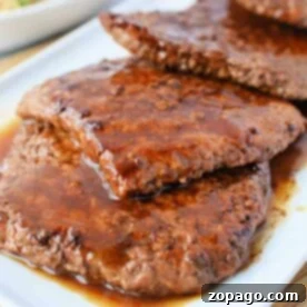 How to Perfectly Pan-Fry Cube Steak 8 Juicy, cooked cube steak slices with sauce on a white plate invite curiosity about how long to cook cube steak in a frying pan for that perfect tenderness.