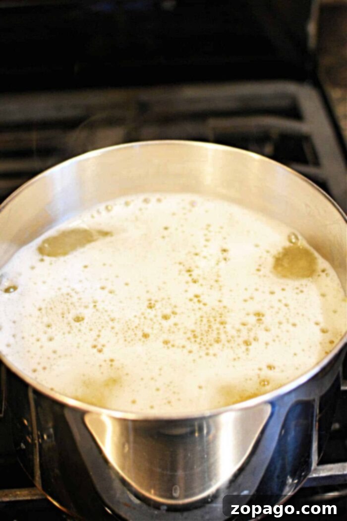 A close-up of a large pot of boiling water with angel hair pasta being added, illustrating the process of how long to cook angel hair pasta.