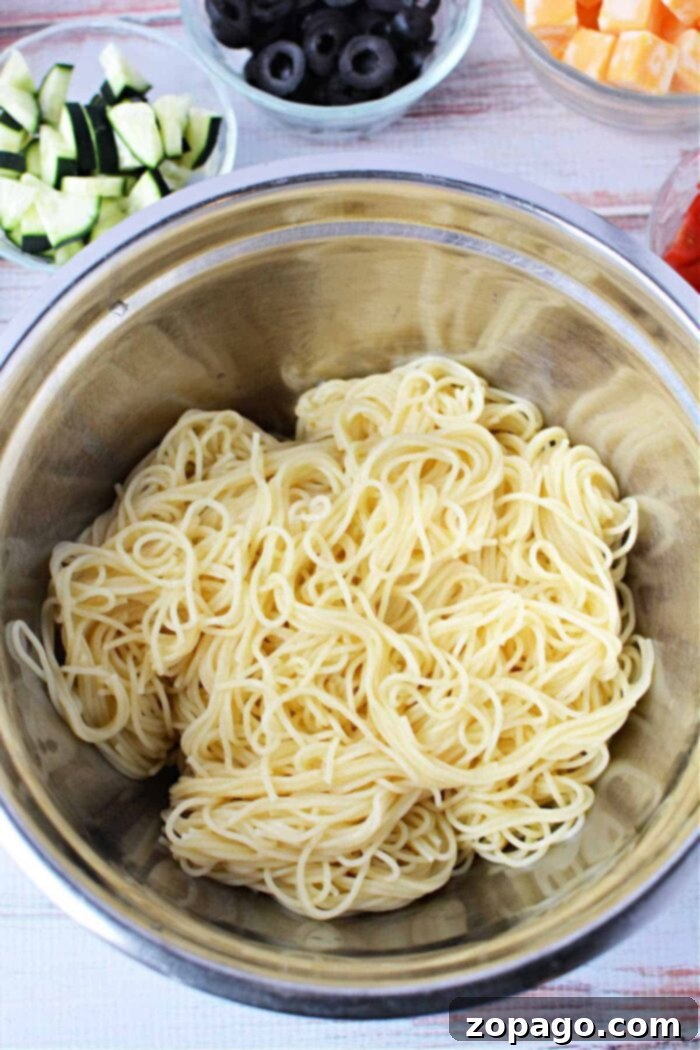 Close-up of cooked angel hair pasta after being drained and rinsed, illustrating its readiness for the salad.