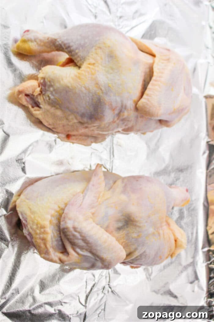 Optimal Roasting Time for Half a Chicken at 400F 4 Two raw half chickens rest on aluminum foil, ready for preparation.
