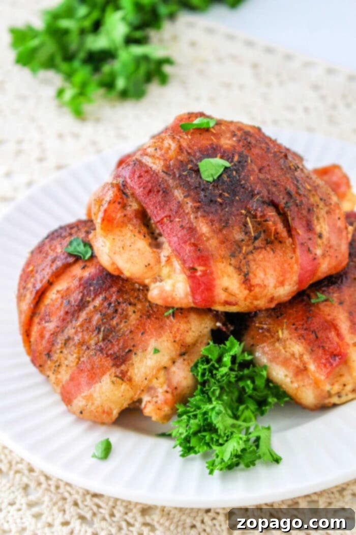 Crispy Bacon Wrapped Chicken Thighs 11 Chicken Thighs Bacon Wrapped, garnished with fresh herbs, ready to be enjoyed.
