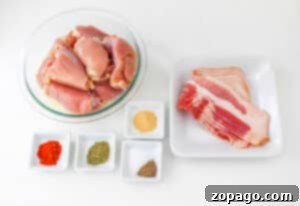 Bacon wrapped chicken thighs and raw bacon with spices rest enticingly on a pristine white surface.