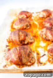 Bacon-wrapped chicken thighs perfectly arranged on a baking sheet, each piece boasting irresistibly crispy edges.