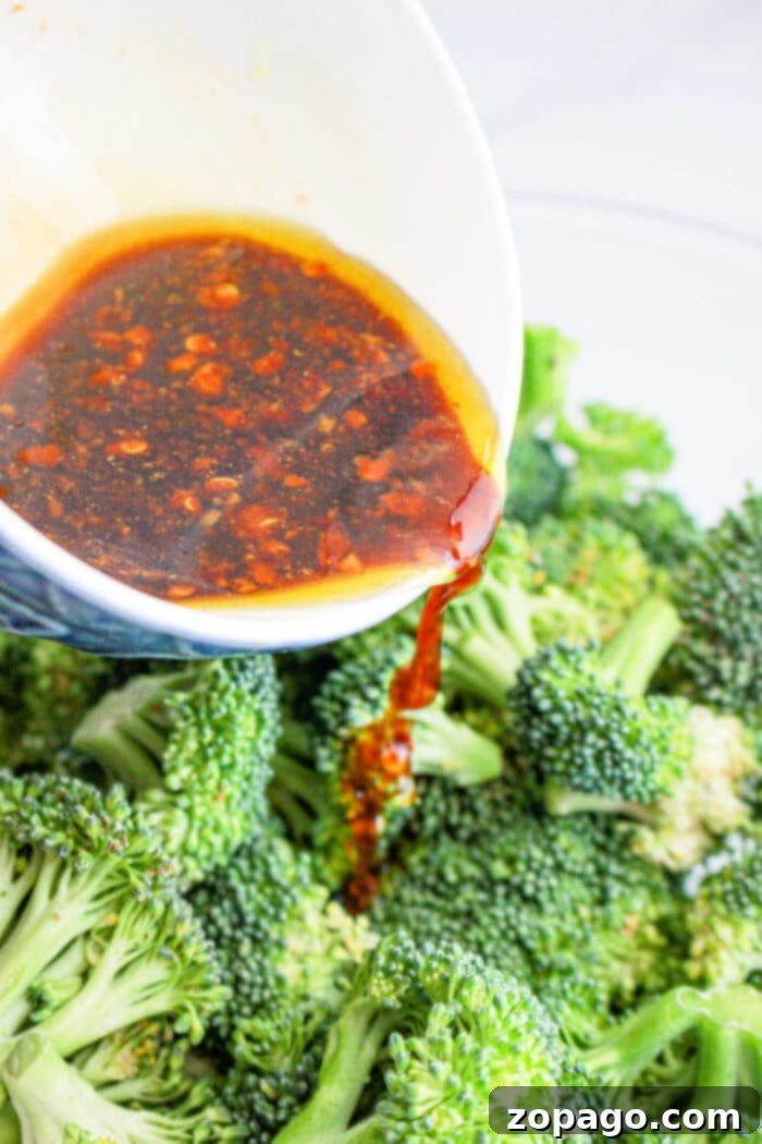 Chinese Broccoli 4 A vibrant bowl of roasted Asian-style broccoli, garnished with fresh green onions and sesame seeds.