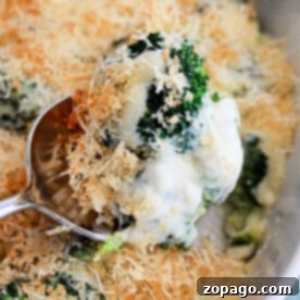 Cheesy Baked Broccoli 9 Close-up of a spoon lifting creamy Broccoli Au Gratin with breadcrumbs and cheese from a dish.