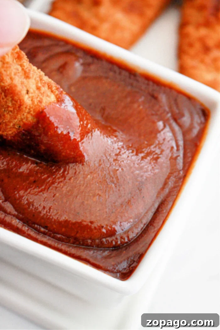Unlock the Secret Popeyes Sauce Recipe 2 Chicken being dipped into rich, homemade Popeyes barbecue sauce in a white bowl