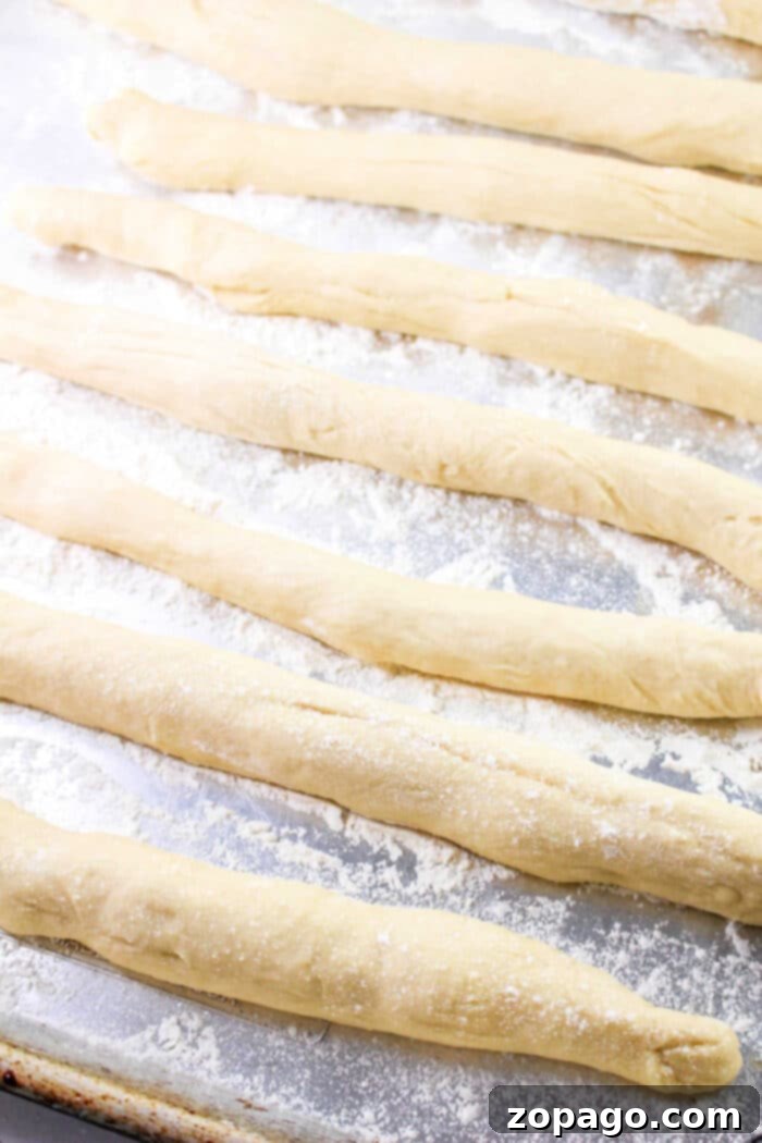 Festive Easter Bunny Buns 7 Raw breadsticks, reminiscent of a classic Bunny Bread recipe, are arranged on a floured baking sheet.