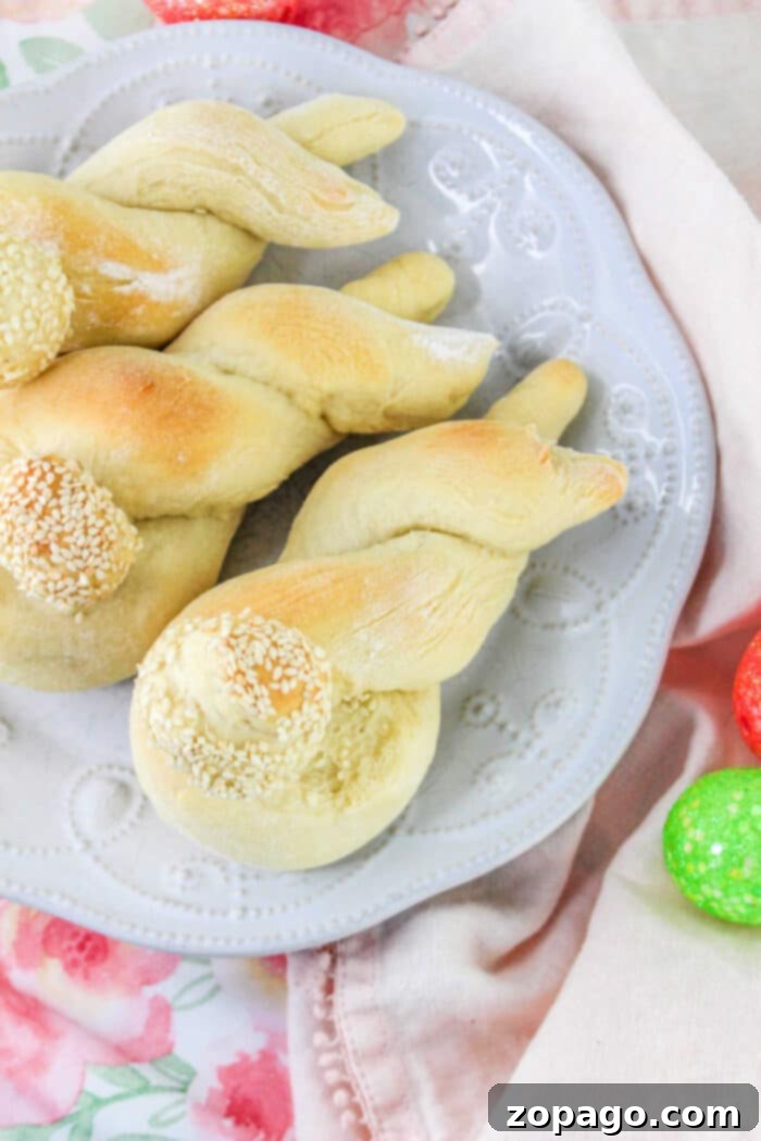 Festive Easter Bunny Buns 9 Twisted breadsticks with sesame seeds on a white plate, surrounded by colorful eggs and a floral tablecloth, offer a festive touch to your Bunny Bread recipe presentation.