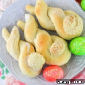 Twisted bread rolls with sesame seeds sit on a plate, surrounded by brightly colored Easter eggs, reminiscent of a delightful bunny bread recipe perfect for celebrating the spring season.