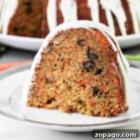 A slice of carrot pound cake with nuts and white icing graces the plate, while the whole cake sits enticingly in the background.