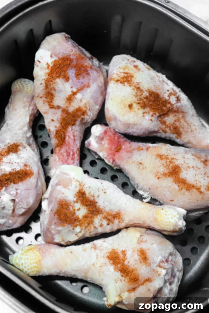 Bone-in chicken legs in air fryer, seasoned and ready for cooking.