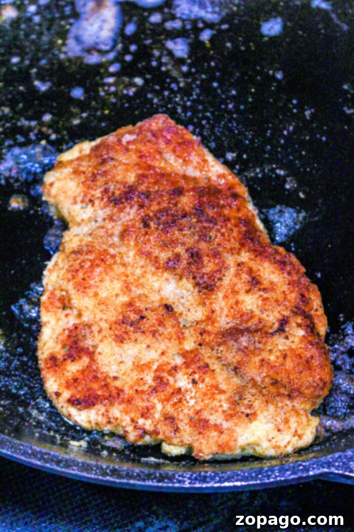 Perfectly Baked Chicken Cutlets 5 Golden brown breaded chicken frying in a black pan with oil bubbling around it, offering a mouthwatering aroma thats hard to resist. While frying creates that crisp crust, for those wondering how long to bake chicken cutlets instead, the oven method ensures juicy tenderness inside.