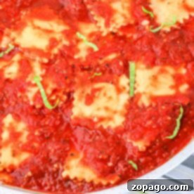 Close-up of frozen ravioli simmering in rich tomato sauce, topped with fresh basil and served invitingly in a pan.