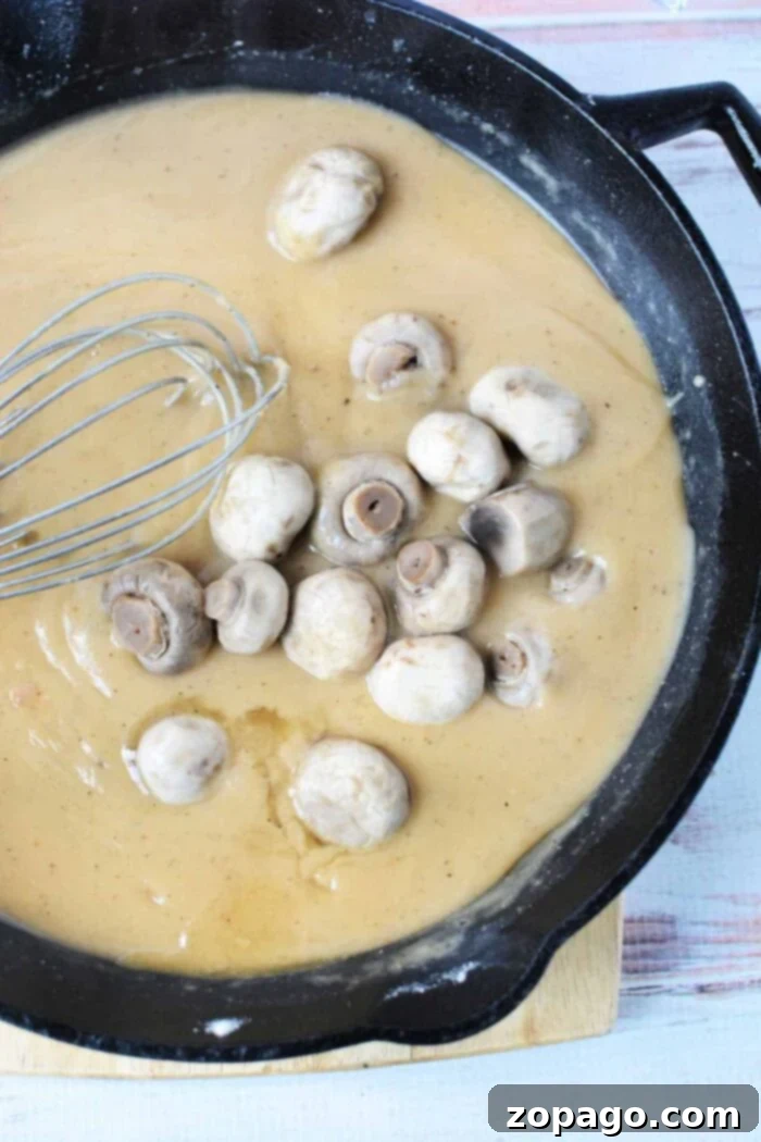 Tender Pork Chops Smothered in Rich Mushroom Gravy 4 A ladle serving thick, creamy mushroom gravy, perfect for accompanying pork.