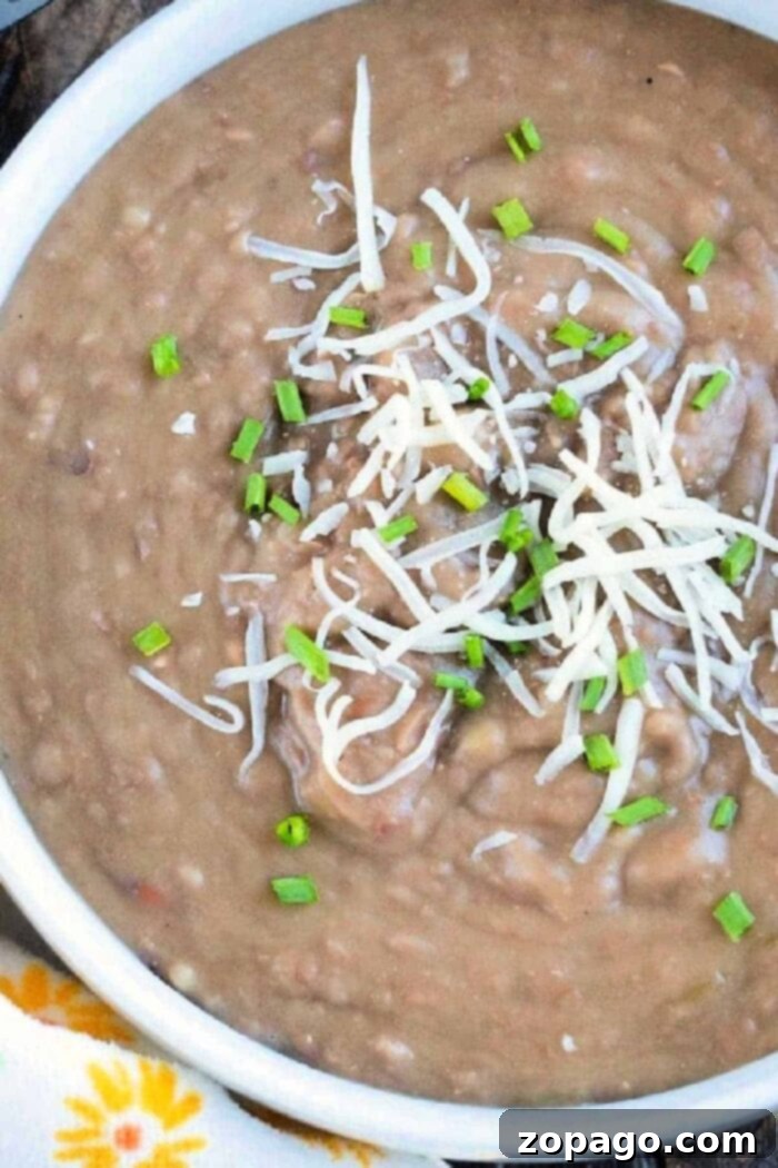 Next Level Canned Refried Beans 4 A close-up of perfectly doctored-up canned refried beans, showing a creamy texture with flecks of seasoning and perhaps a hint of added ingredients, making them look irresistible.