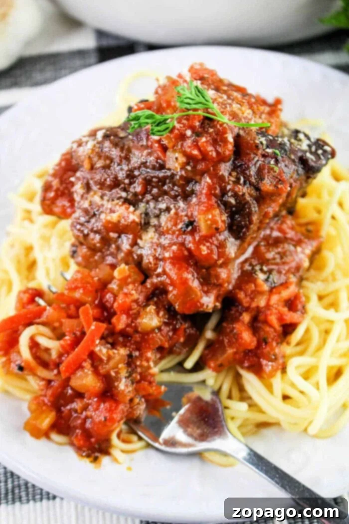 Slow-Cooked Short Rib Tacos 7 A plate of spaghetti topped with a hearty portion of meat sauce garnished with herbs sits invitingly on a checkered cloth. A fork rests on the edge, ready for use, reminiscent of the anticipation before savoring delicious short rib tacos.