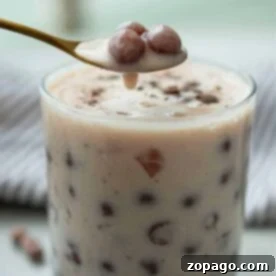 Perfect Homemade Boba for Bubble Tea 7 A glass of creamy bubble tea showcases a spoon lifting perfectly cooked tapioca pearls, set against a soft focus background. Learn how to cook boba for bubble tea and achieve this delightful texture at home.