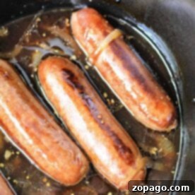 Crockpot brats simmer gently in a pot of rich broth, mingling with sliced onions to create a savory aroma thats hard to resist.
