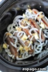 Crockpot Brats combined with sliced onions, garlic, and butter create a mouthwatering slow-cooker delight.