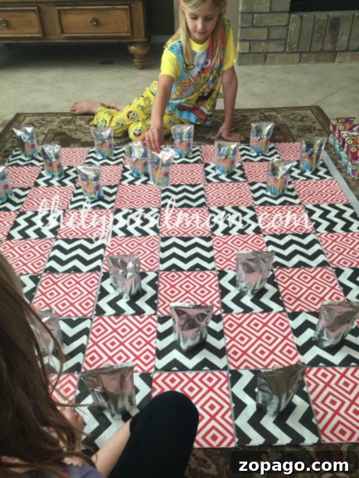 Family Game Night: Kids Enjoying DIY Giant Checkers with Capri Sun Pouches Two children playing giant checkers on the DIY board made from a tablecloth and napkins, using Capri Sun pouches as game pieces. Highlighting fun games to play at home with kids.