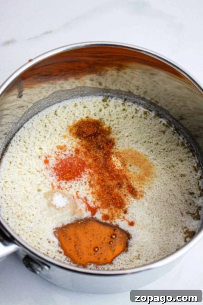 Homemade Hot Honey: Sweet Heat Perfection 5 Close-up of hot honey sauce simmering in a saucepan with a whisk