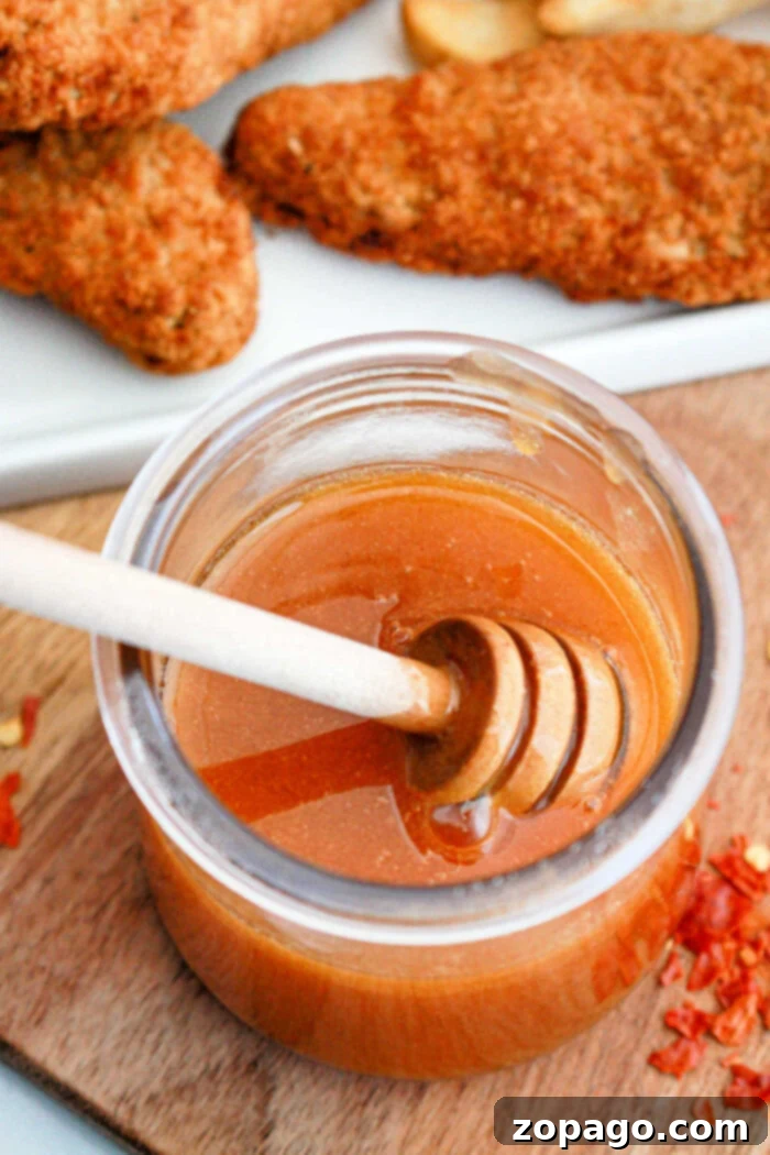 Whip Up Your Own Hot Honey 6 A jar of homemade Copycat Mike's Hot Honey sauce with a honey dipper, ready for serving.
