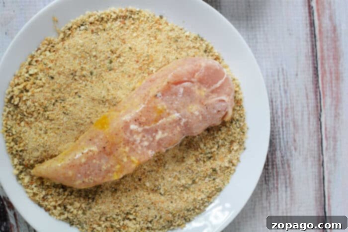 Mastering Crispy Homemade Chicken Tenders 5 Learn how to make chicken tenders by breading raw chicken breast on a white plate, achieving that perfect crispy texture.