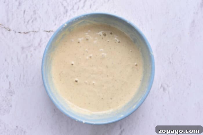 Perfect Beer Batter Every Time 4 A bowl of beer batter sits on a light gray textured surface, reminiscent of the smooth preparation for a perfect beer batter halibut.