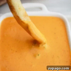 A fry being dipped into a square dish of creamy orange sauce, reminiscent of the tangy kick from KFCs Buffalo Ranch recipe.