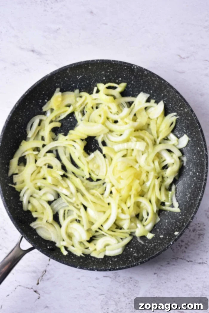 Sweet Caramelized Onion Confit 4 Close-up of golden onion confit simmering gently in olive oil within a pan, showcasing its rich texture and luscious sheen.