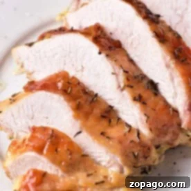 A close-up of several slices of cooked turkey breast confit on a white plate. The turkey has a crispy, browned skin with herbs visible on the surface. The inside appears tender and juicy.