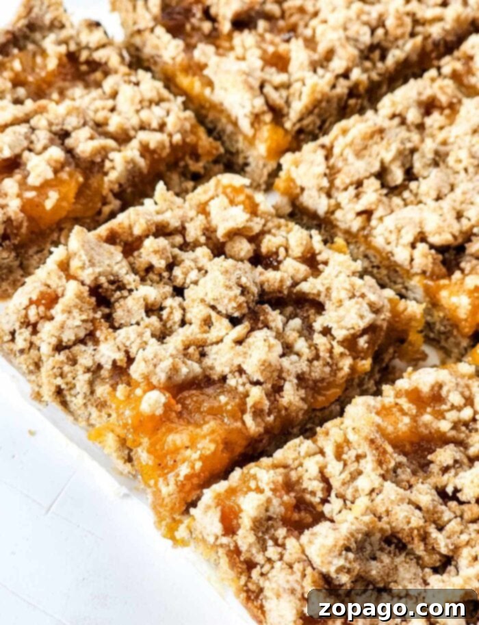 Easy Peach Crumble Bars 2 Irresistible golden-brown peach crumb bars with a generous crumble topping, artfully sliced and arranged for serving.