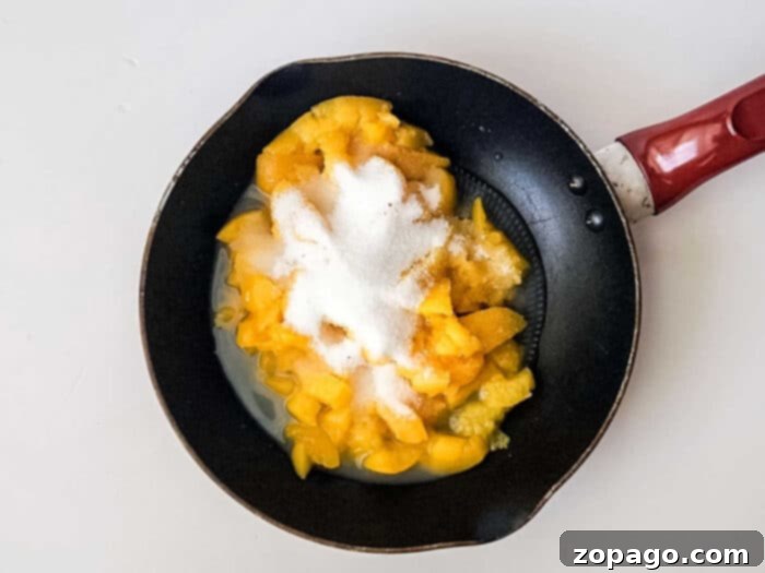 Easy Peach Crumble Bars 4 A frying pan filled with plump, chopped peaches, glistening with sugar and warm spices, simmering into a rich and aromatic filling for peach bars.