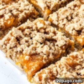 Easy Peach Crumble Bars 9 Close-up of peach bars with a crumbly topping, arranged in a grid pattern on a white surface, capturing the sweet charm of summer in each bite.