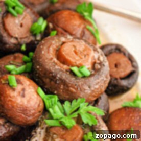 Crockpot mushrooms cooked to perfection, garnished with fresh parsley and chopped green onions on a plate.