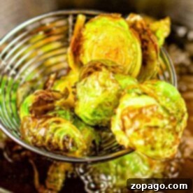 Deep fried Brussels sprouts are expertly scooped from the hot oil with a wire skimmer, ensuring a perfectly crispy texture.