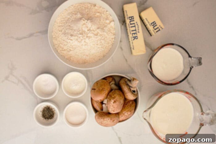 A top-down view of cooking ingredients on a white marble surface. There are flour, two sticks of butter, milk, cream, whole mushrooms, and small bowls containing salt, pepper, and sugar—perfect essentials for preparing Slow Cooker Biscuits and Gravy.